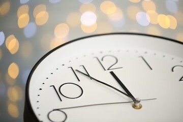 Clock showing five minutes until midnight on blurred background, closeup. New Year countdown