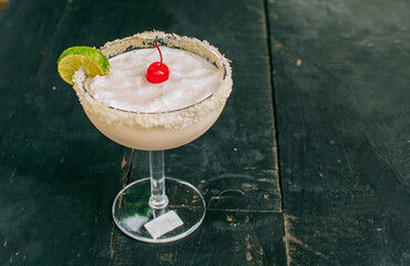 Frozen coconut margarita with lemon slice served on wooden table. Close up of delicious frozen...