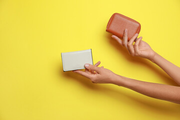 Woman holding leather purse on yellow background, closeup. Space for text