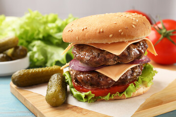 Tasty hamburger with patties, cheese and vegetables served on table, closeup