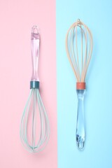 Two whisks on color background, top view