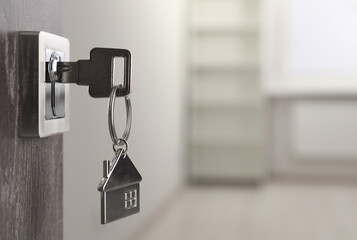 Mortgage and real estate. Open door with key and house shaped keychain against blurred background, space for text - obrazy, fototapety, plakaty