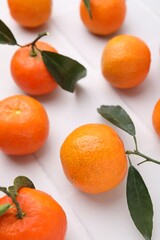 Fresh ripe tangerines with green leaves on white table