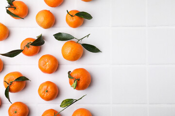 Fresh ripe tangerines with green leaves on white table, flat lay. Space for text