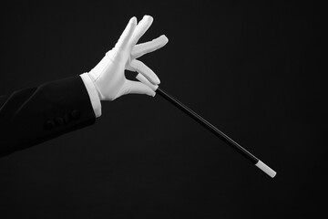 Magician holding wand on black background, closeup