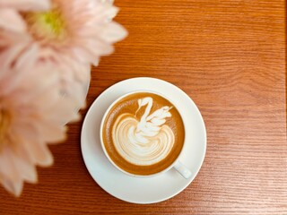 Latte art, coffee latte art with swan pattern, blurred foreground, coffee cup on wooden table