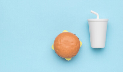 A white drink glass and a hamburger on a blue background.