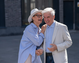 Stylish elderly laughing couple on a walk. Romantic relationships of mature people. 