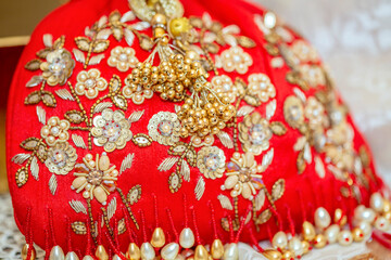 Close-up of golden floral embroidery with pearls on bright red fabric conveying luxury and intricate craftsmanship