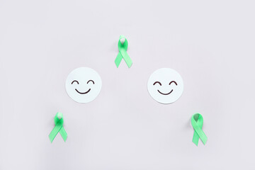 Happy smile faces with green awareness ribbons on grey background. Mental Health Day