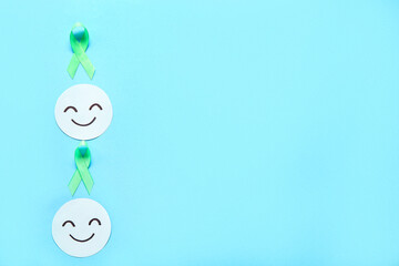 Happy smile faces with green awareness ribbons on blue background. Mental Health Day