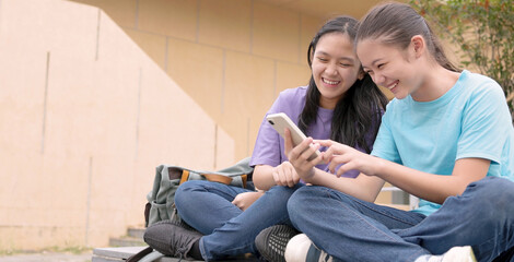 Happy Asian student girls using smart phone in school