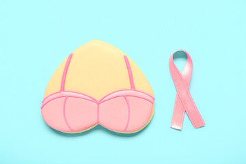 Heart shaped cookie with bra and pink ribbon on blue background. Breast cancer awareness concept