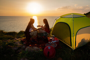 Two female hikers set up camp on a seaside cliff.