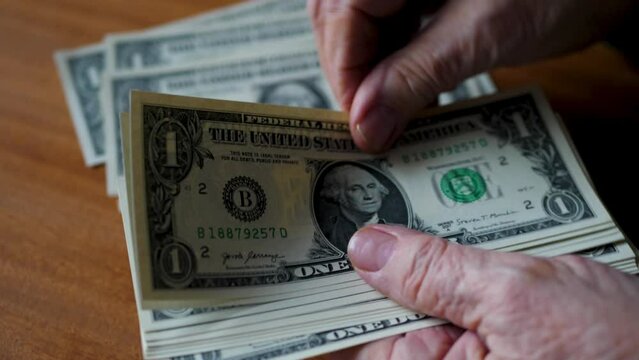 Old Woman's Hands Counting a Stack of US Dollar Bills
