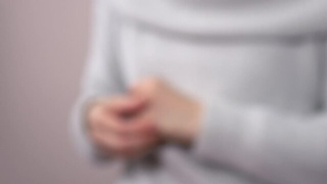 Blurred, closeup shot of a young woman scratching her hands. 4K