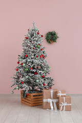 Decorated Christmas tree with gifts against pink wall