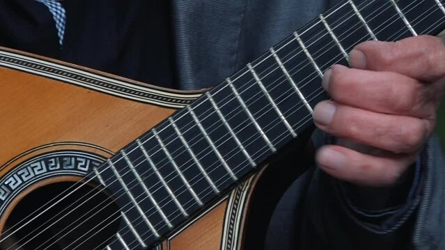 Fingers plucking a traditional Portuguese guitar. close up