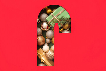 Cut red paper in shape of candy cane with Christmas gift and balls on green background