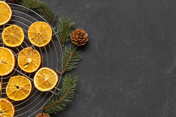 Stand of dried orange slices with fir branches and pine cone on black background
