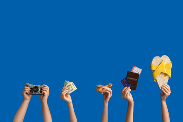 Female hands with sandals, photo camera, wooden plane, documents and money on blue background