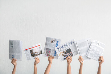 Female hands with different newspapers against light background - obrazy, fototapety, plakaty