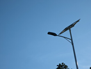 A sole solar street light during a clear sunny morning. Large solar panel mounted on top of the pole. Optical weather conditions to recharge.