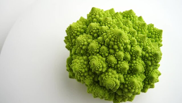 Fresh raw cauliflower romanesco rotating on white background.Green Head of Cabbage with Close up slow motion shot. Romanesco broccoli, Roman cauliflower, Broccolo Romanesco