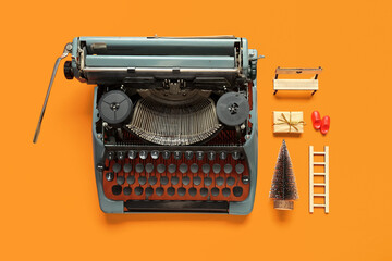 Fototapeta na wymiar Vintage typewriter with Christmas decor on orange background