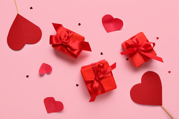 Gift boxes with paper hearts and confetti on pink background. Valentine's Day celebration