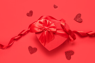 Gift box with ribbon and hearts on red background. Valentine's Day celebration