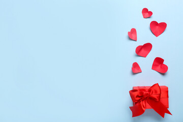Gift box and paper hearts on blue background. Valentine's Day celebration