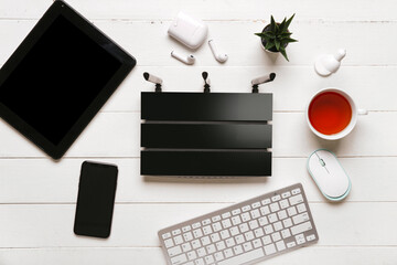 Modern wi-fi router with keyboard and mobile phone on white wooden background