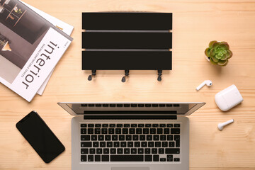 Modern wi-fi router with mobile phone, laptop and magazines on wooden background