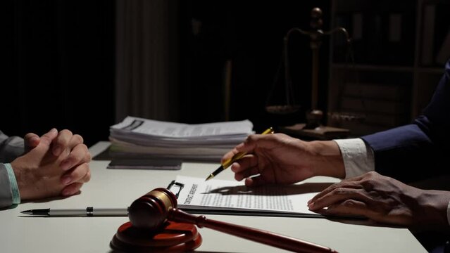 Businessmen and lawyers read details of legal agreements Signing investment contracts in financial businesses, banks, and real estate with the hammer of justice in the office.