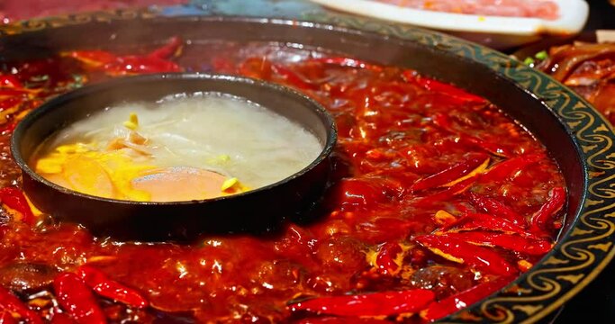 Chinese spicy hot pot cuisine. A layer of red chili pepper floats in the boiling hot pot base. Famous Chongqing Spicy Hot Pot, China.