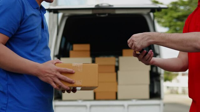 Delivery man, driver in red orange uniform is sending parcel box package from cargo truck at home to customer' hands then sign and cash on delivery for parcel by cross-border QR payment