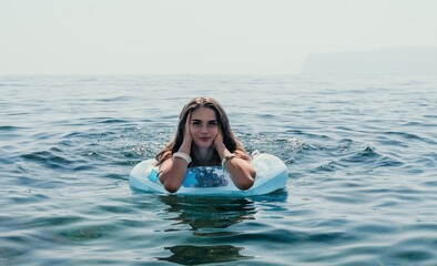Woman summer sea. Happy woman swimming with inflatable donut on the beach in summer sunny day, surrounded by volcanic mountains. Summer vacation concept.