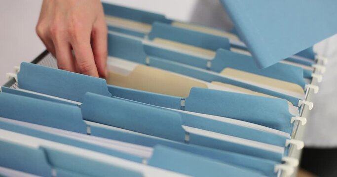 Manager secretary puts folder with connecting files in box stored in office