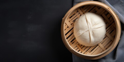 Top view of a gray background with a Bamboo steamer containing a Korean street food: Pyanse steamed bun. - obrazy, fototapety, plakaty