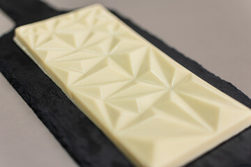piece of white chocolate on a black board. creamy snack. sugarless