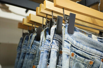 Jeans on the hanger in the store. Clothes on hangers in shop for sale. Blur background. Fashionable...