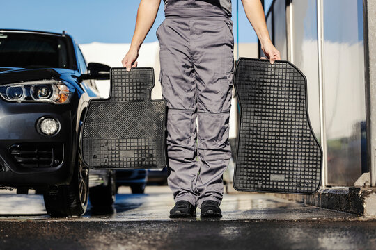 Cropped picture of an unrecognizable worker holding a car floor mats.