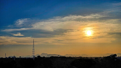 Naklejka premium Silhouettes of the electric power masts and cables, Pylons against sunset over countryside. The sunset and electrical network. High-voltage power lines at sunset. Electricity distribution station.