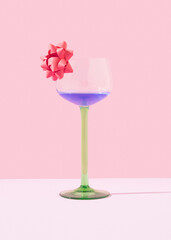 Cocktail glass with bow. Purple drink. Concept of party, special moments, Christmas, new year, easter, birthday, Valentine. Copy space. Pastel pink background. Front view.