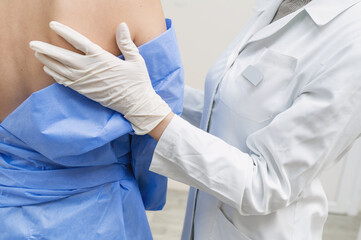 The doctor supports and encourages the patient. A woman's hand in a rubber disposable glove gently and carefully touches the patient's back during a mammography. medical care and responsive nurse