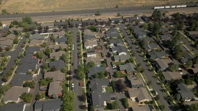 Drone shot tilting up from a suburban neighborhood to the nearby train tracks cutting through Bend, Oregon.