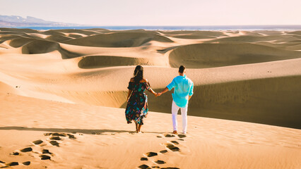 couple walking at the beach of Maspalomas Gran Canaria Spain, men, and woman at the sand dunes...