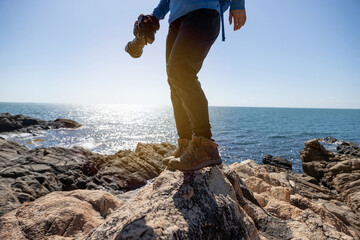  Woman photographer walking on sunrise seaside rocky mountains