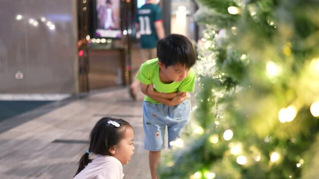 Happy kindergarten child boy and girl enjoying with gift decoration on christmas tree